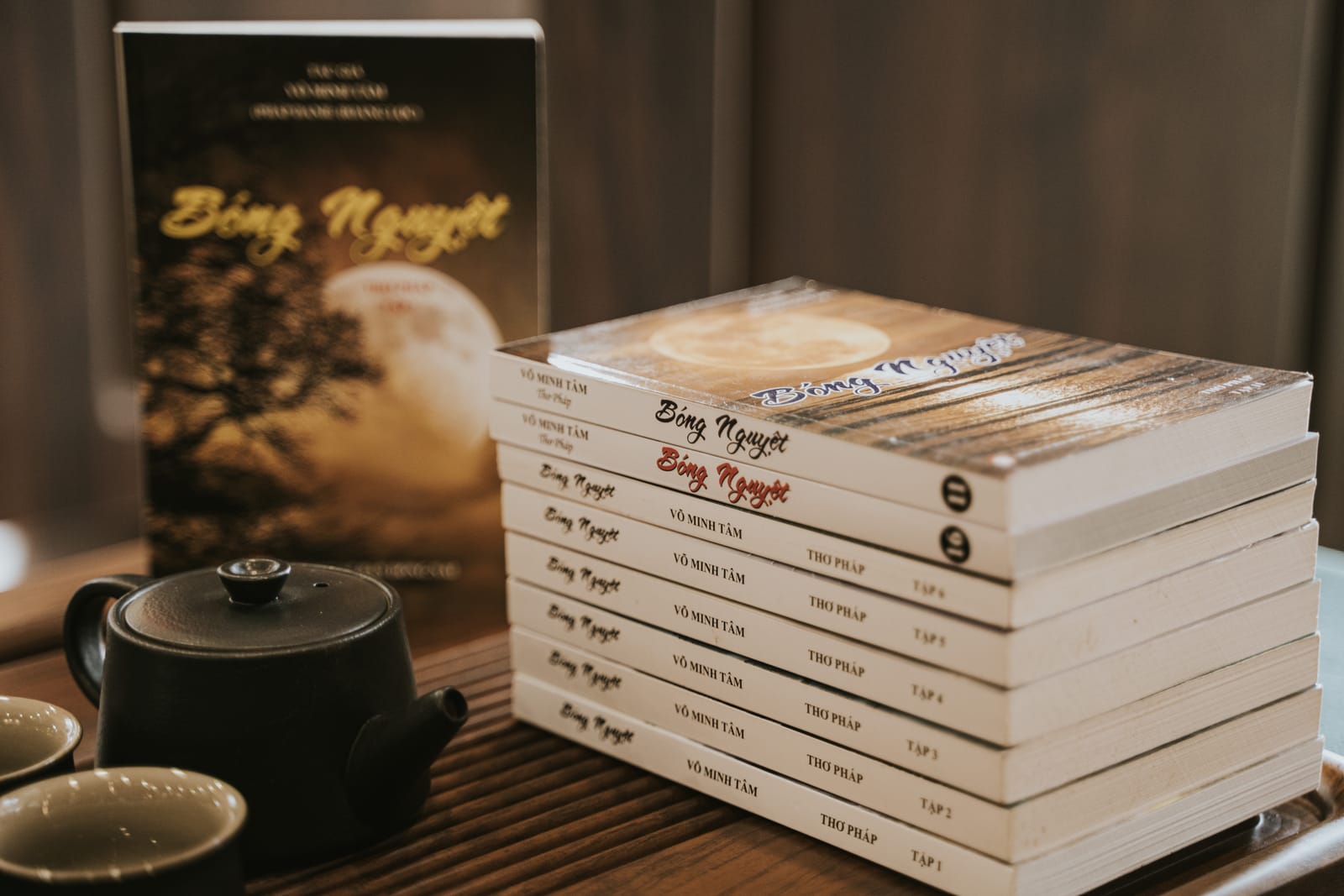 Chồng sách Bóng Nguyệt đặt cạnh khay trà.