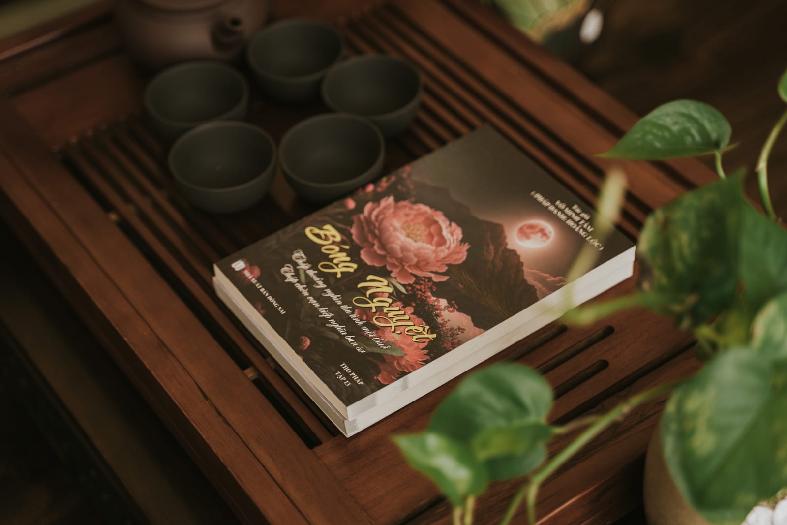 Khay trà với những chiếc chén nhỏ, sách nằm cạnh.